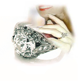 Close up picture of diamond ring, with a woman's hand wearing a diamond ring in the background